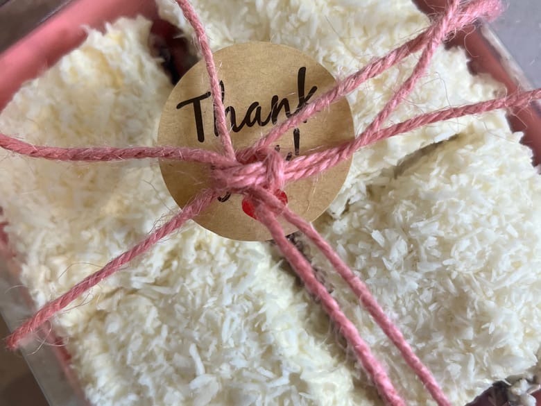 Coconut slices in a gift box with a pink ribbon and thank you tag
